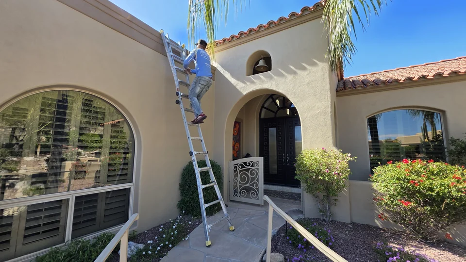 Blueprint team member on a ladder at a tile-roof home